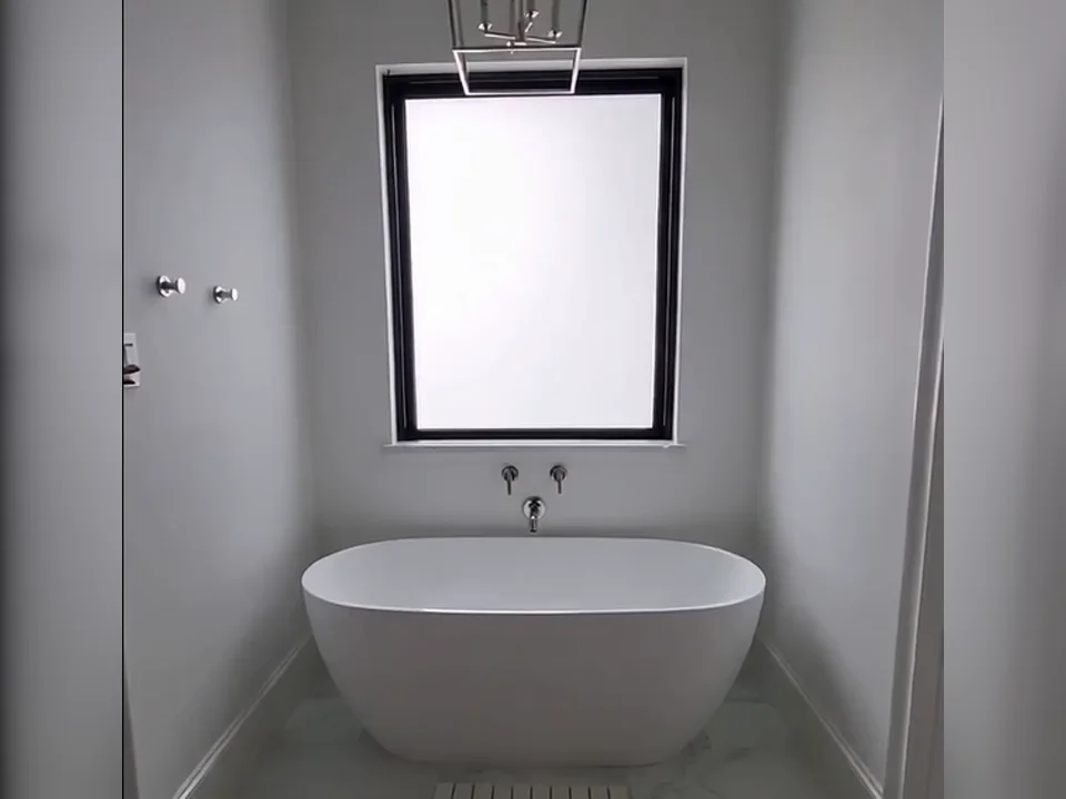 Bathroom window above a freestanding tub with installed Smart Film